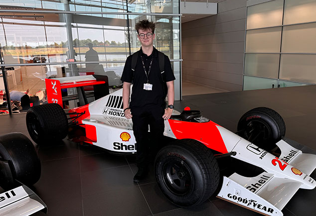 Male student standing next to F1 race car